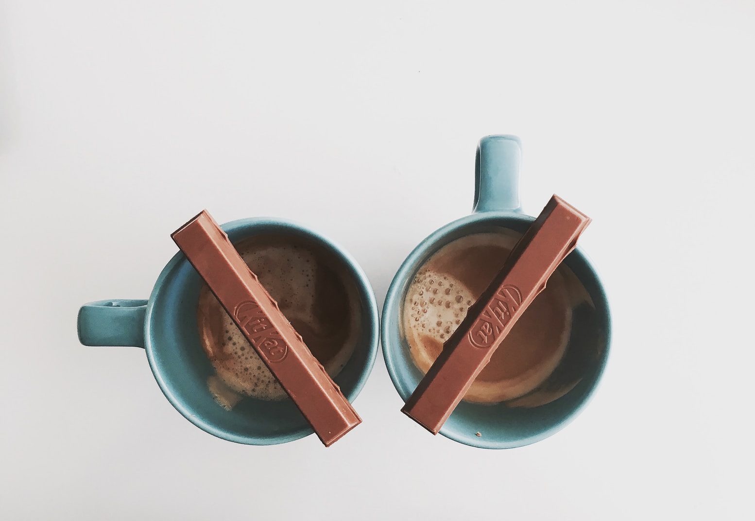 two green ceramic cups with chocolate bar on top